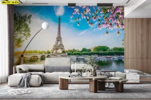 ห้องนั่งเล่นโมเดิร์นผนังพาโนรามาแม่น้ำและหอไอเฟล เสริมมุมมองสะพาน-เรือ ท้องฟ้าสดใส กิ่งดอกชมพูพาดกรอบภาพ จับคู่โซฟาสีอ่อน พรมเทา โต๊ะไม้หิน สื่ออารมณ์ชิลแบบยุโรปร่วมสมัย