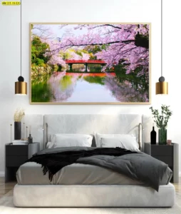 ภาพกรอบวิวซากุระเหนือสายน้ำกับสะพานสีแดงสะท้อนเงา โทนชมพูเขียวละมุน ติดผนังเหนือเตียงสไตล์โมเดิร์น เสริมบรรยากาศญี่ปุ่นสงบอบอุ่นสำหรับงานตกแต่งภายใน