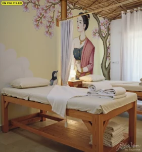 วอลเปเปอร์ลายไทยประยุกต์ ภาพหญิงสาวใต้ต้นไม้สีชมพูบานสะพรั่ง ตกแต่งห้องนวดสปาเตียงไม้ ให้ความรู้สึกอ่อนหวานและนุ่มนวลชวนพักผ่อน